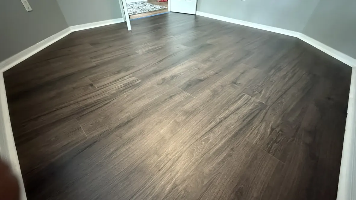 Dark vinyl plank flooring installed in a living room with a bay window