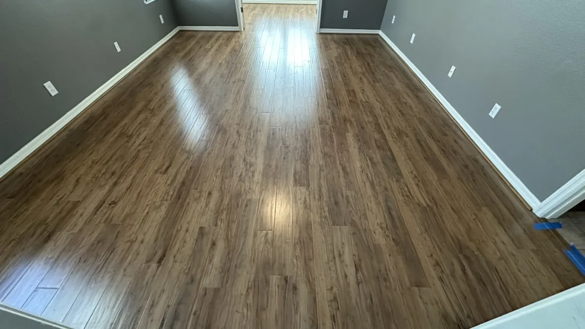 Dark vinyl plank flooring in a room with a blue accent wall