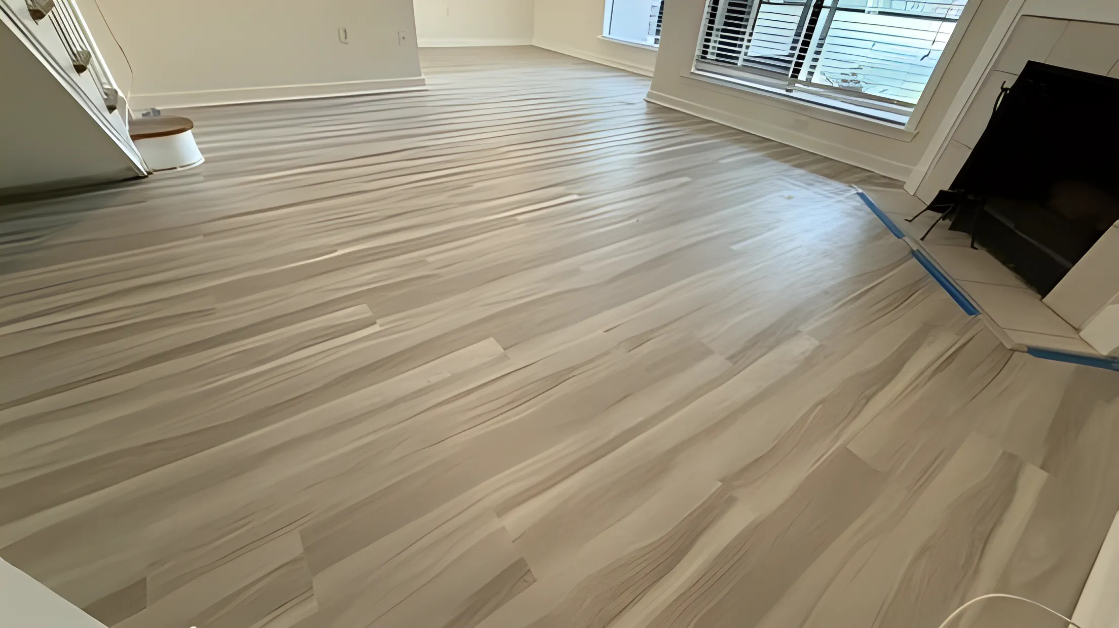 Gray vinyl plank flooring in a bright empty room with large windows