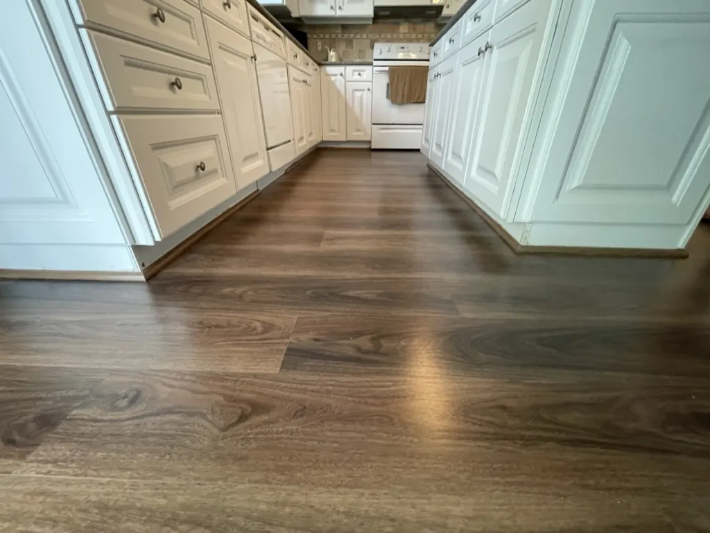 Dark vinyl plank flooring in a kitchen with white cabinetry
