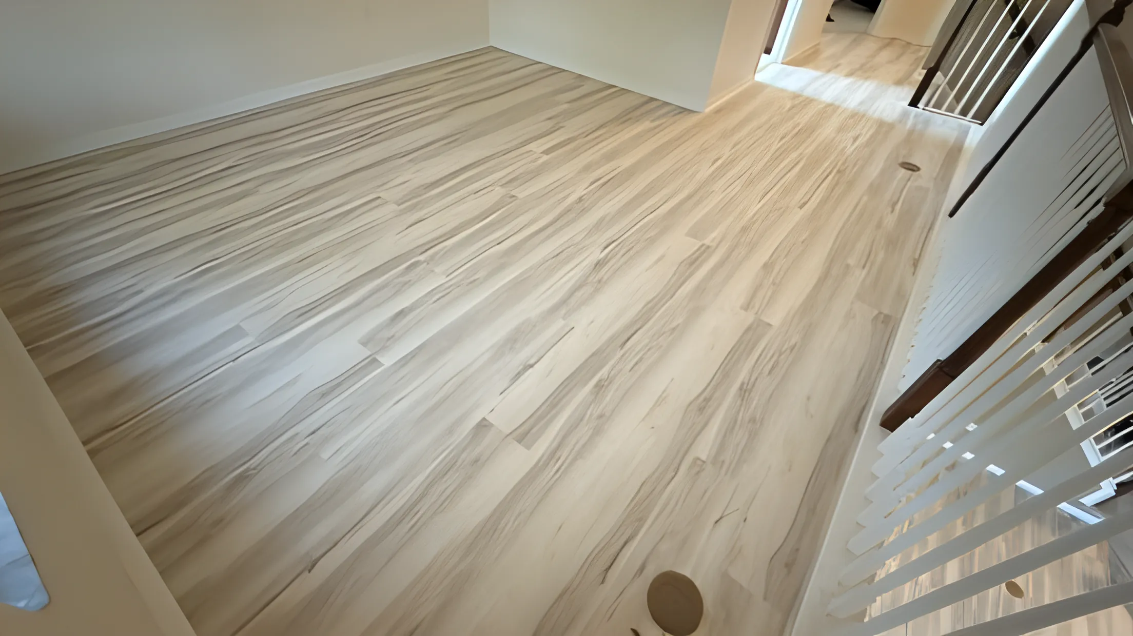 Light vinyl plank flooring beside a white stair railing