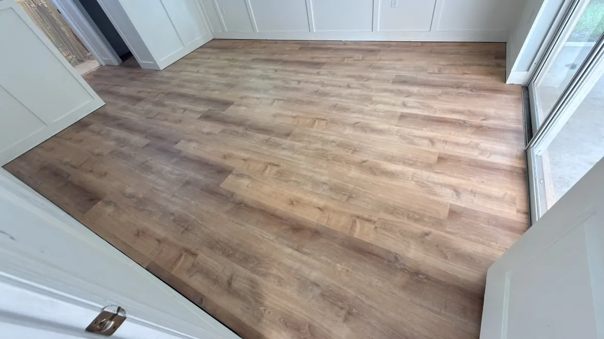 Dark vinyl plank flooring installed against white wainscoting