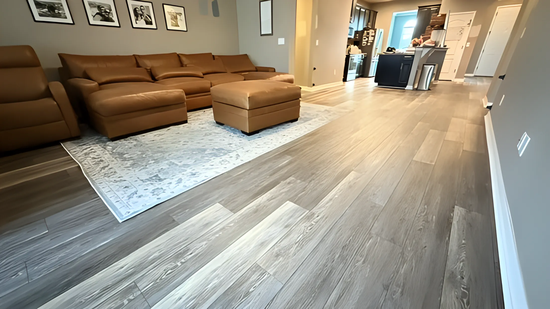 Gray luxury vinyl plank flooring installed in an open living room with area rug
