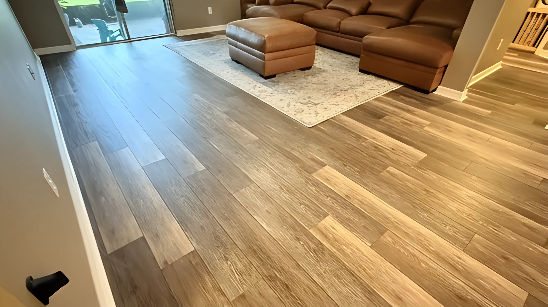 Wide plank vinyl flooring in a living room with leather sectional