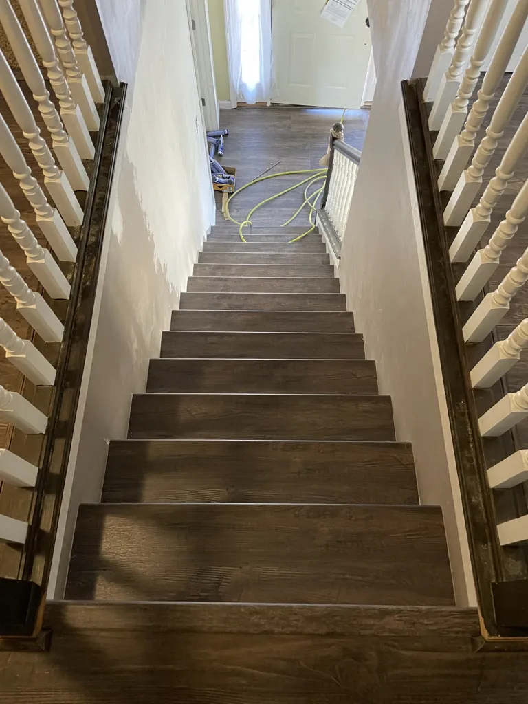 Dark wood stair treads viewed from an upstairs hallway