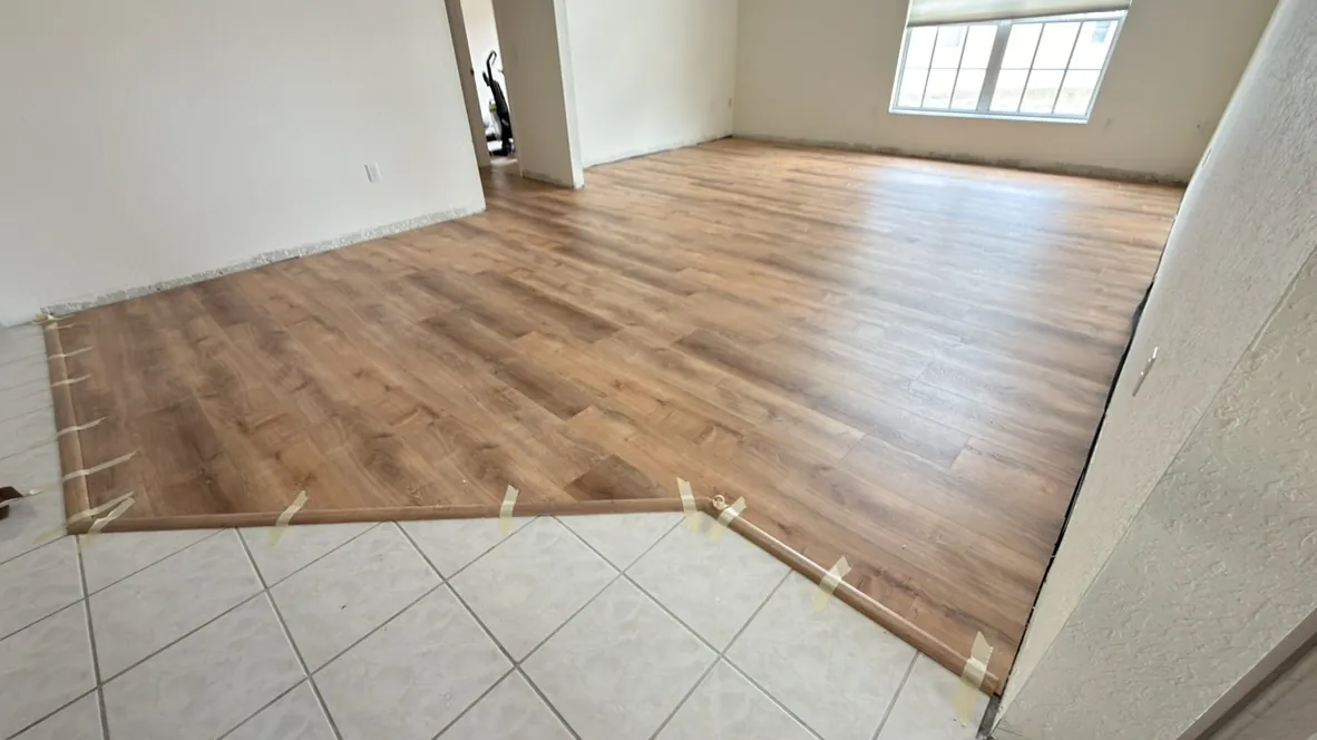 Wood flooring transitioning to existing tile in an open room